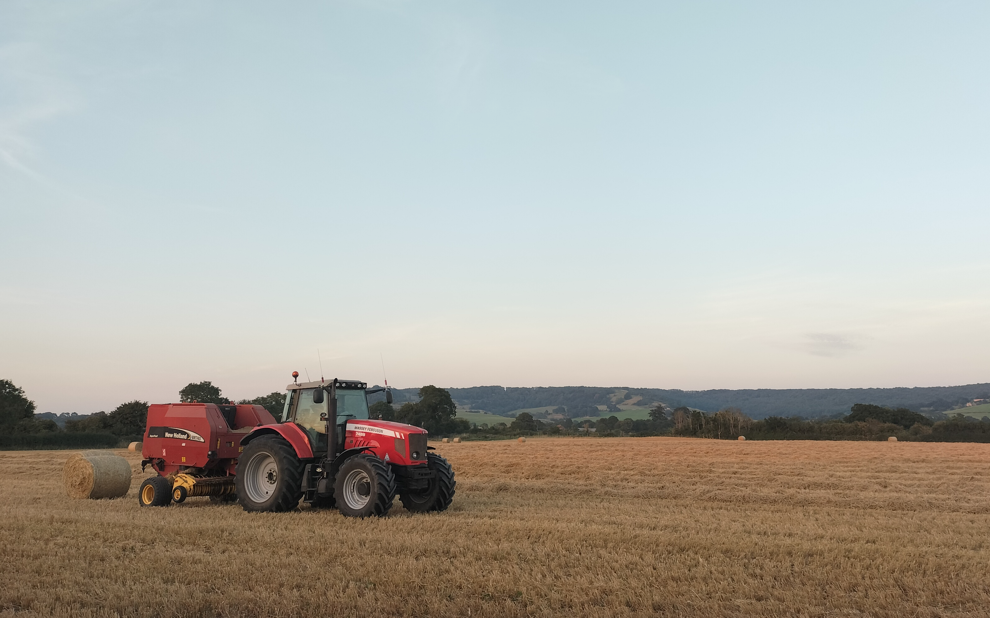 Cotswold contractors  with Round baler at Upton Saint Leonards